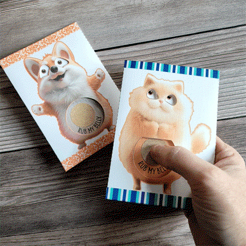 Two novelty craft books placed on a wooden surface, each featuring an animated animal character with a tactile belly. The left book shows a fluffy orange cat with the phrase 'Rub My Belly' and the right book depicts a playful orange and white corgi with 'Rub My Belly' written below. Both have a circle cut-out at the belly filled with a textured material for sensory interaction.