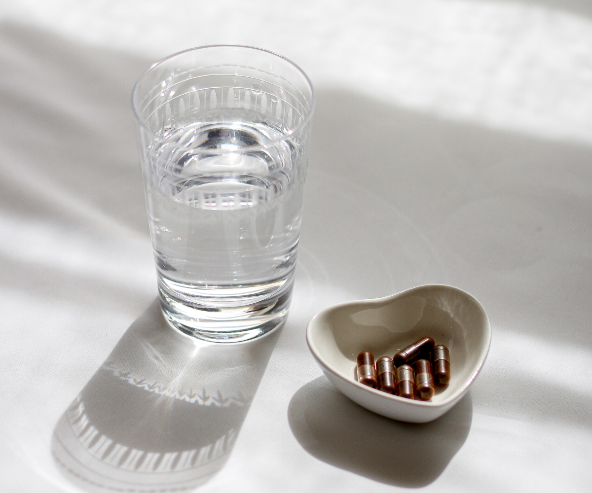 Astaxanthin capsules in a heart shaped dish with a glass of water