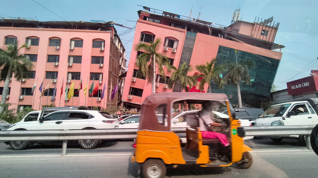 Motorists ride past a bright pink damaged building after a strong earthquake struck central Myanmar, in Mandalay, Myanmar.