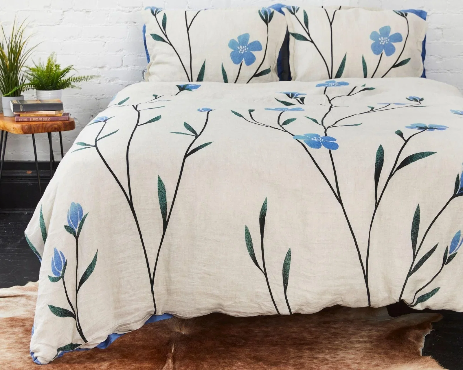 a bed with a white comforter with blue flowers on it