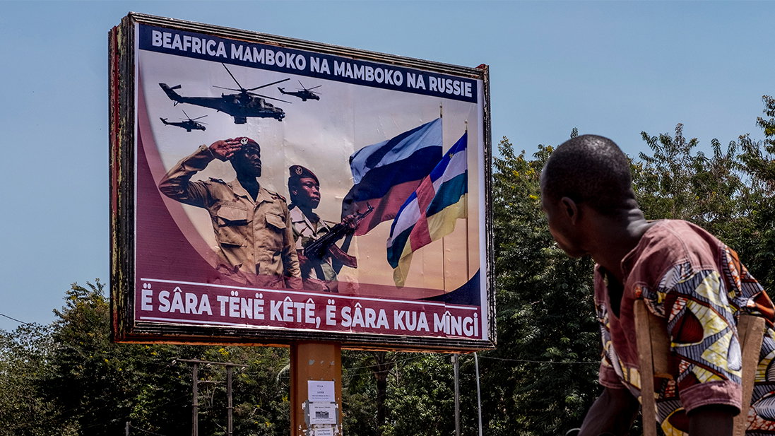 A man with crutches looks at a large bilboard sign proclaiming collaboration between Russian and the Central African military in downtown Bangui, Central African Republic