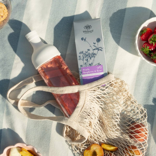 Image of our hario bottle with peach, raspberry rose loose leaf time in a summer picnic bag