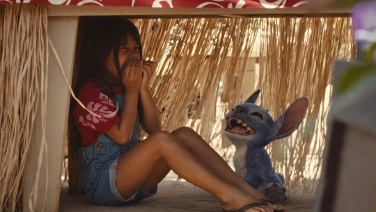Lilo and Stitch laugh under a table in a scene from Disney's live-action 'Lilo & Stitch'