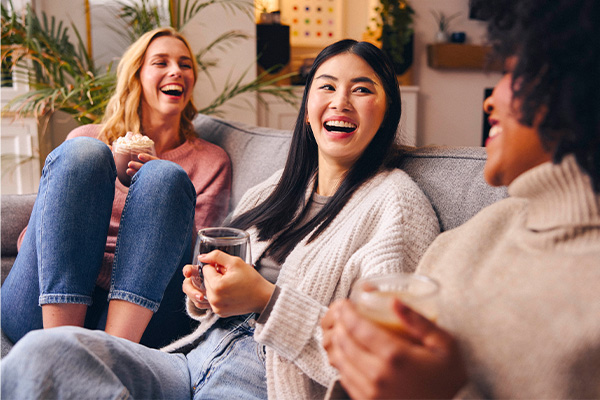 A group picture of three friends laughing on the sofa drinking Whittard tea, coffee and hot chocolate