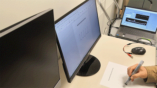 A short clip from a video of an individual with Parkinson’s disease using the diagnostic pen for a writing task, with data being recorded on computer screens.