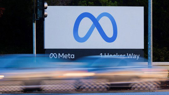Cars blurred by motion pass the Meta headquarters sign at 1 Hacker Way