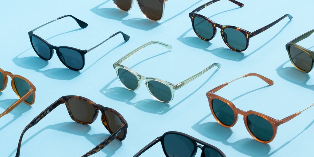 Several pairs of sunglasses sit on a light blue background.