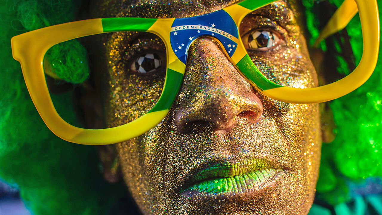 A Brazilian football supporters wears football contact lenses and Brazilain flag glasses. 