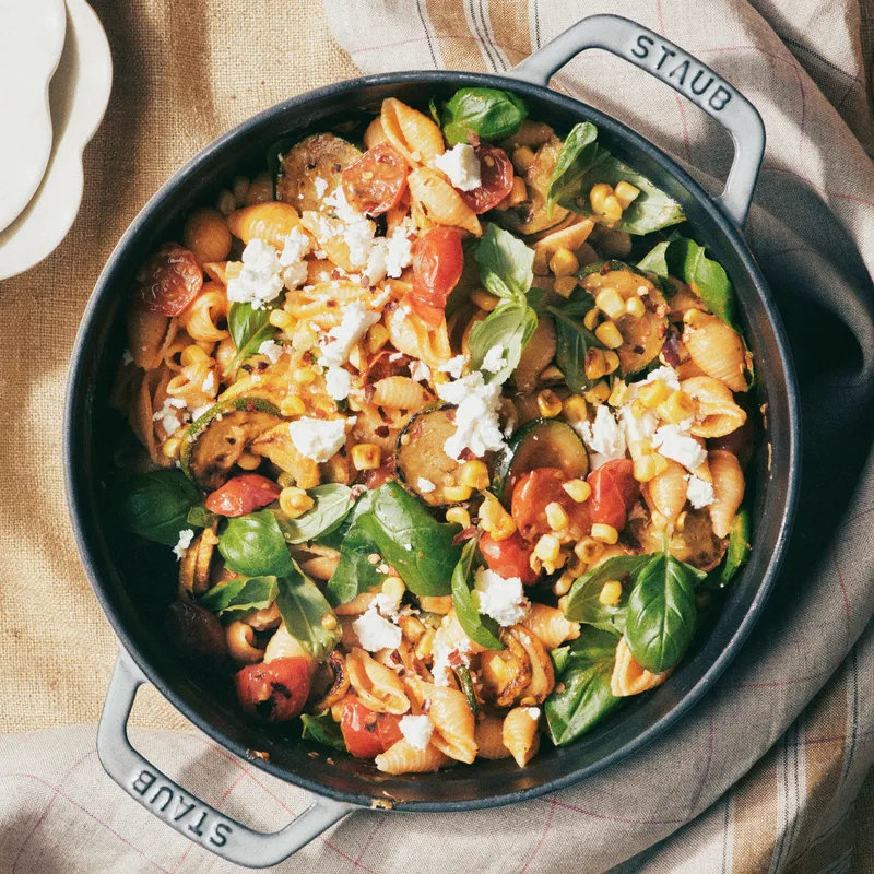 Pasta shells, sliced zucchini, sliced summer squash, cherry tomatoes, Japanese eggplant, roasted corn, Parmesan cheese, crumbled feta, red pepper flakes, and fresh basil leaves in a dutch oven and served with white wine.