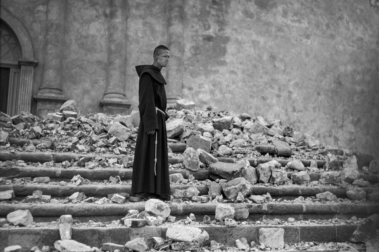 A friar stands on the steps of the earthquake damaged Mission Santa Barbara.