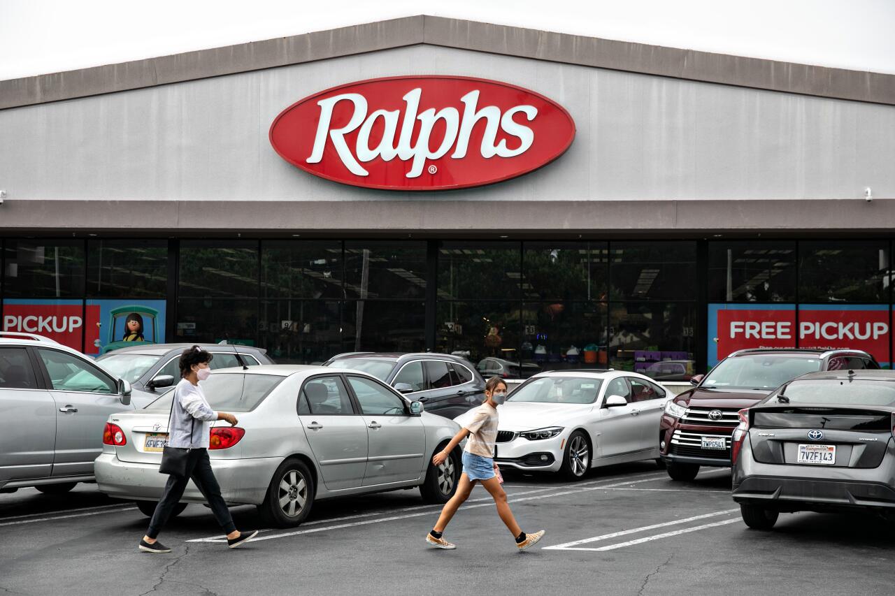 Shoppers walk in the parking lot of a Ralphs grocery store.