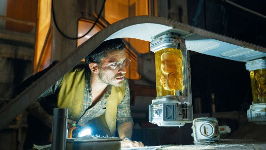 A character in the latest "Jurassic Park" examines a specimen in a laboratory