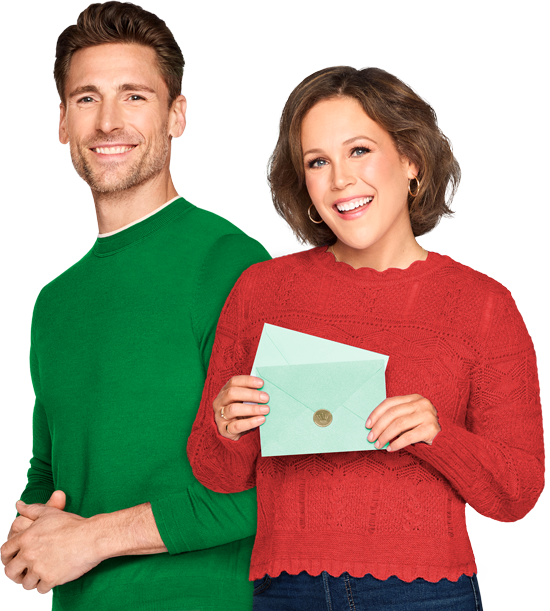 Hallmark stars Andrew Walker and Erin Krakow smiling, wearing holiday clothes and holding Hallmark green card envelopes.