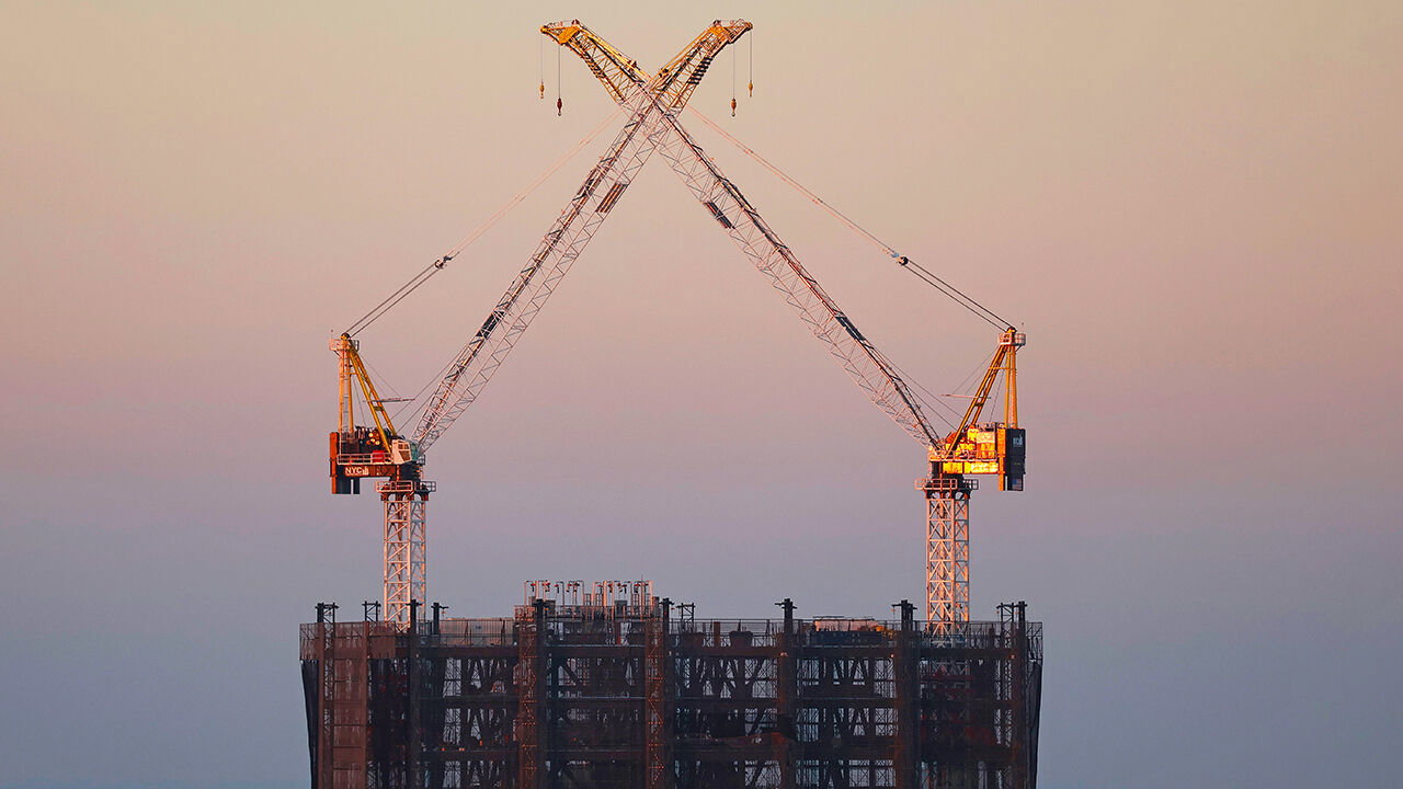Two cranes stand atop the under-construction building in New York