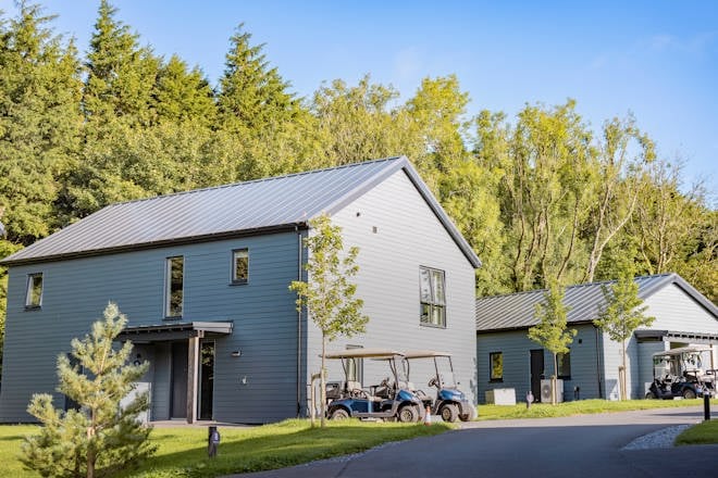 Carningli Lodge set against a background of trees with a blue sky