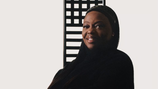 Pat McGrath smiles in front of a black-and-white lattice