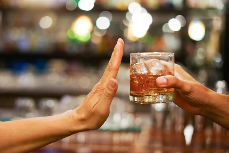 A hand held out, palm up, to refuse a cocktail being held toward it.