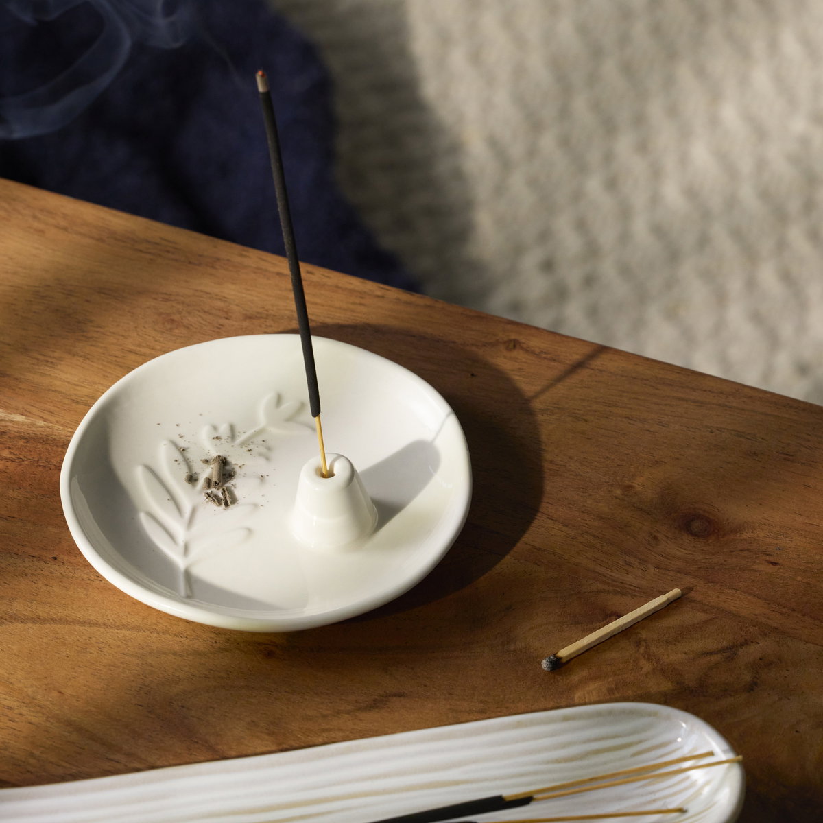 Incense burner and incense stick on a table.