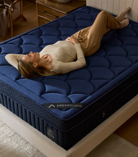 a woman is laying on a blue dreamcloud mattress