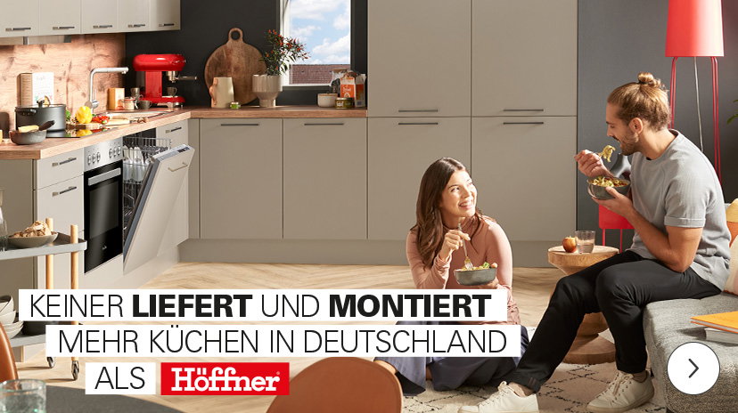 Eine Werbeanzeige für Küchen, die einen lächelnden Mann mit einer Tasse in einer modernen weißen Küche mit goldenen Akzenten zeigt. Die Anzeige bewirbt "1/2 Preis für frei geplante Küchen" und "bis zu 5 Jahre keine Zinsen".