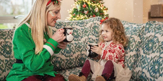 elf sharing a hot chocolate with a young girl