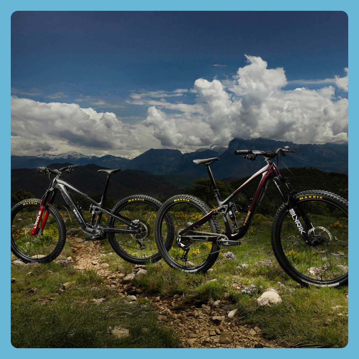 All-new 2026 mountain bikes on grass and rocky dirt trail with mountains and clouds in background