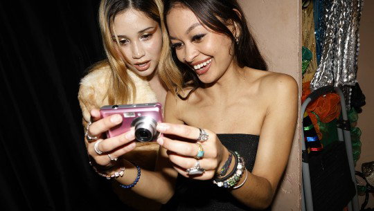 Two women look at the display of a digital camera