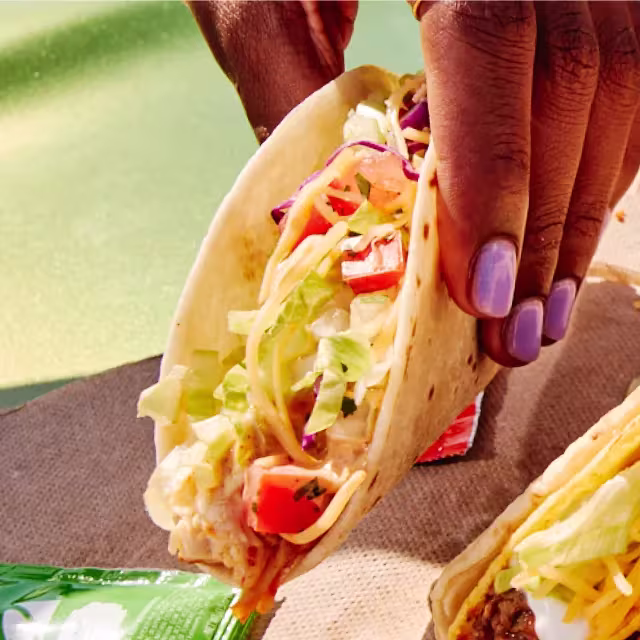Person picking up a Cantina Chicken Soft Taco.