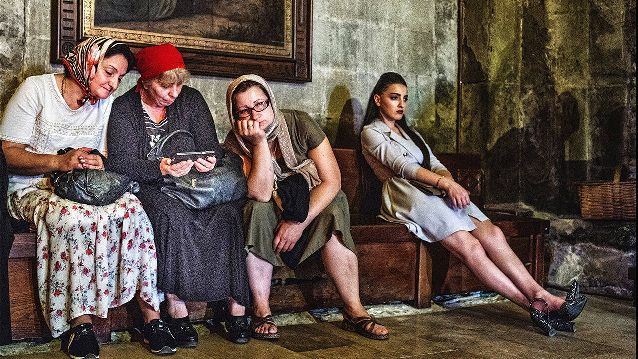 Women listen to the priest on a smartphone in the Svetitskhoveli Cathedral, an Unesco heritage complex.