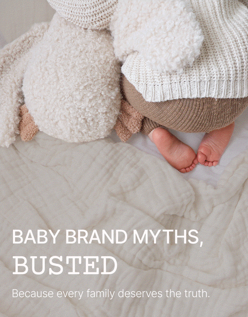 Close-up of a baby lying on a textured cream blanket wearing a knitted beige jumper, soft light highlighting the yarn pattern beside the text “Baby Brand Myths, Busted.”