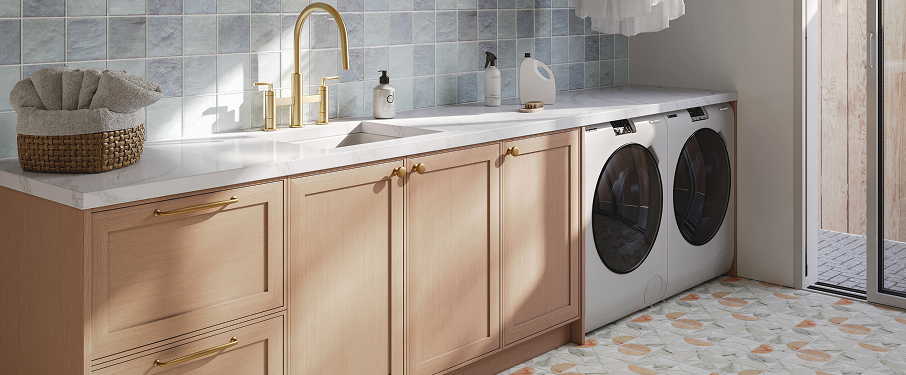 Laundry room close-up of blonde color cabinets, white countertops, and gold faucets.