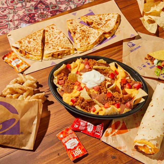 Various Taco Bell menu items on a walnut-brown wood living room table.