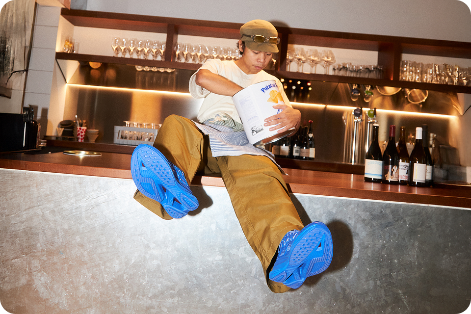 Person sitting on a bar counter eating crisps and wearing Mach X Caged in Ultra Marine/ Midnight Blue.