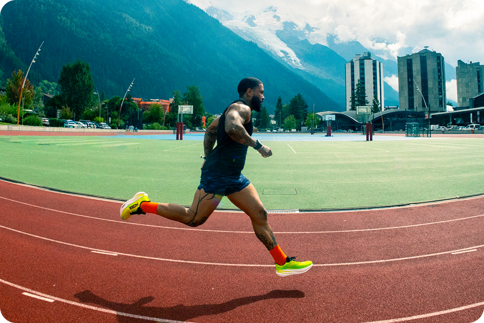 Person running on a track with mountains in the background wearing Mach X 3 in neon hoka citrus / neon lime.