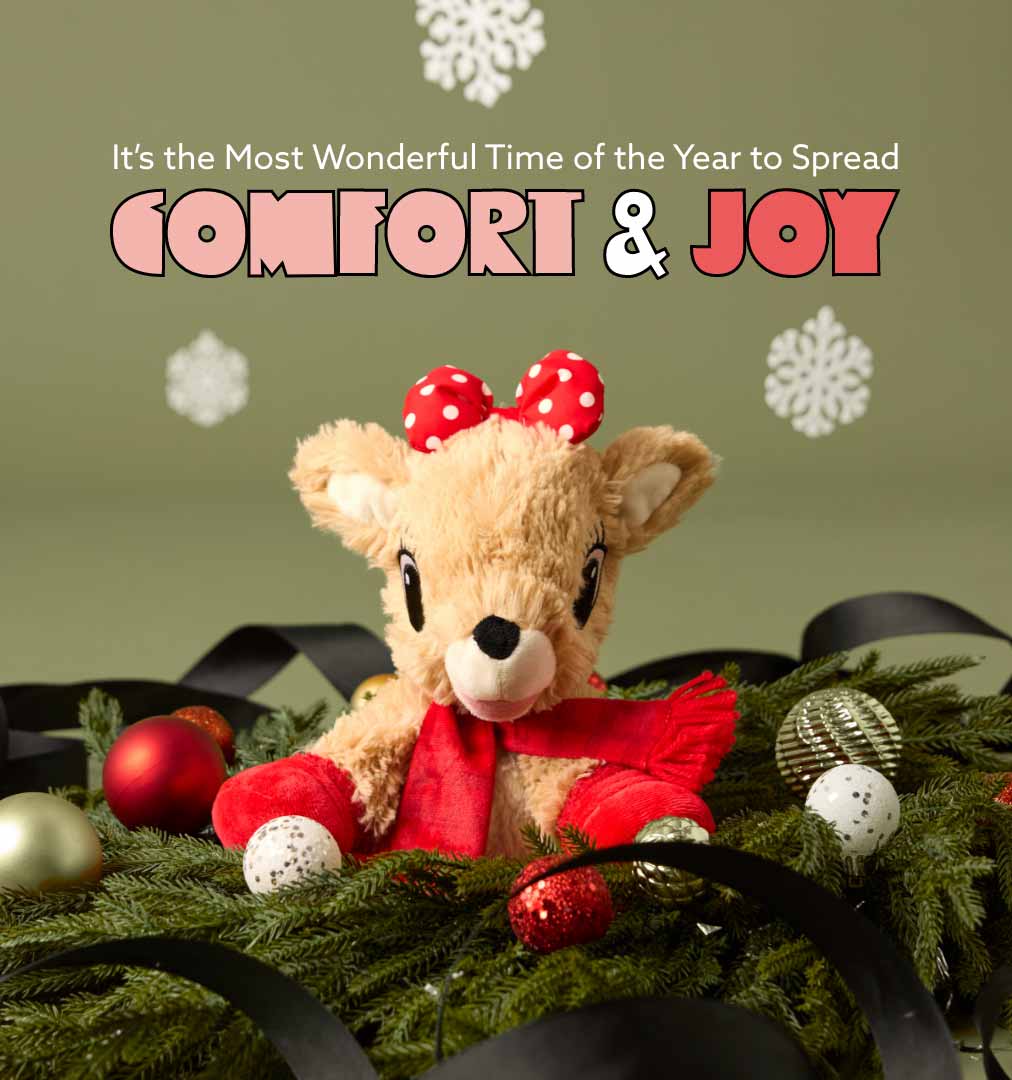 Clarice Warmies on a Christmas wreath with ornaments and ribbons. Shop Black Friday Sale.
