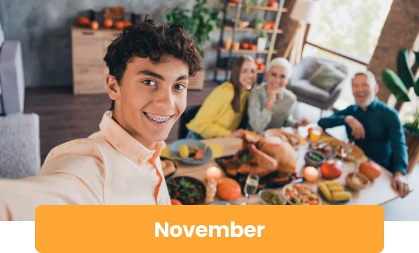 Photo of a boy taking a selfie with his family at the holiday table. Beneath the image is the word November.