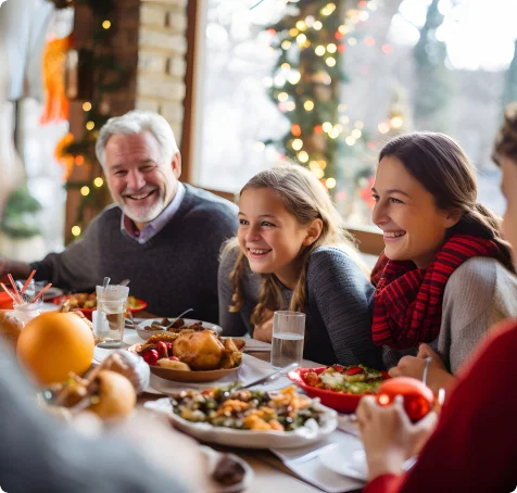 A family is shown laughing together at a holiday dinner table.