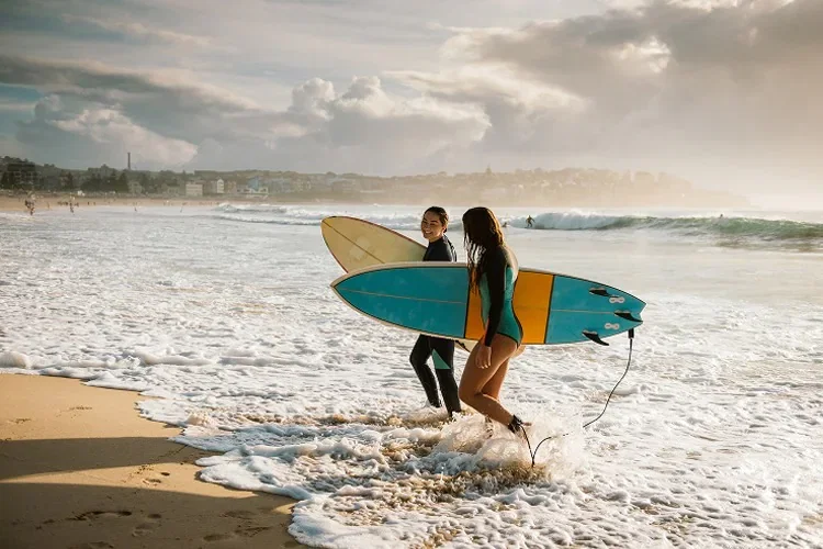 Two surfers return to shore as waves rush over their feet
