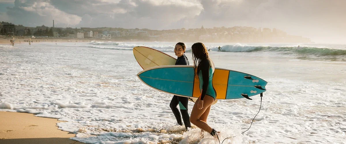 Two surfers return to shore as waves rush over their feet