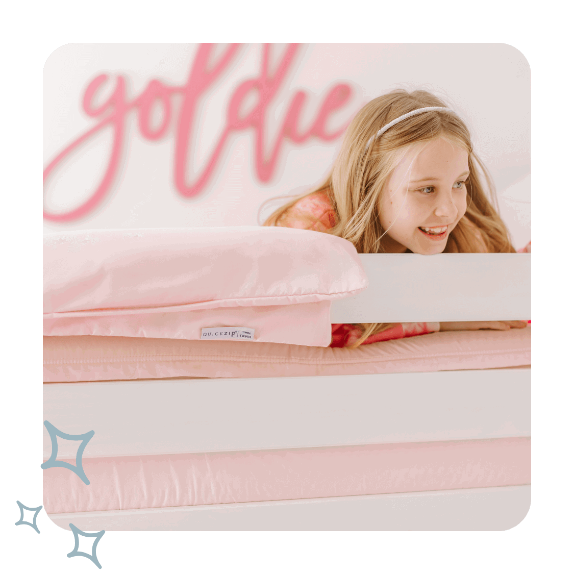 A girl lays in a bed with pink sheets
