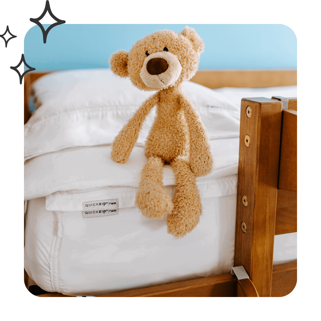 A corner of a bunk bed with white sheets and a teddy bear