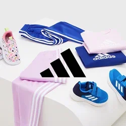 Odzież Adidas wystawiona: różowa koszula, niebieskie spodnie, różne buty i wzorzyste klapki. Materiały to tkanina i guma; kolory są żywe.