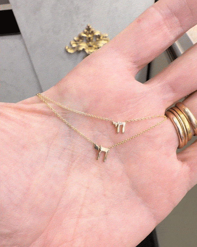 Hand holding gold Chai Necklaces