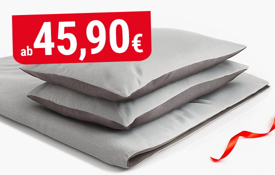 Eine gefaltete Decke und zwei Kissen bezogen mit der BODYGUARD Flanell-Bettwäsche. Davor eine Luftschlange. Text: ab 45,90€