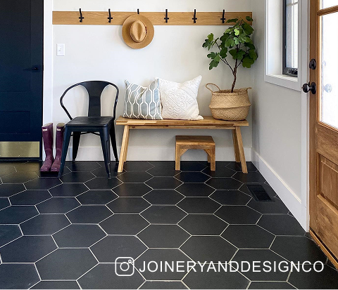 An entryway in a house featuring black hexagonal porcelain flooring.