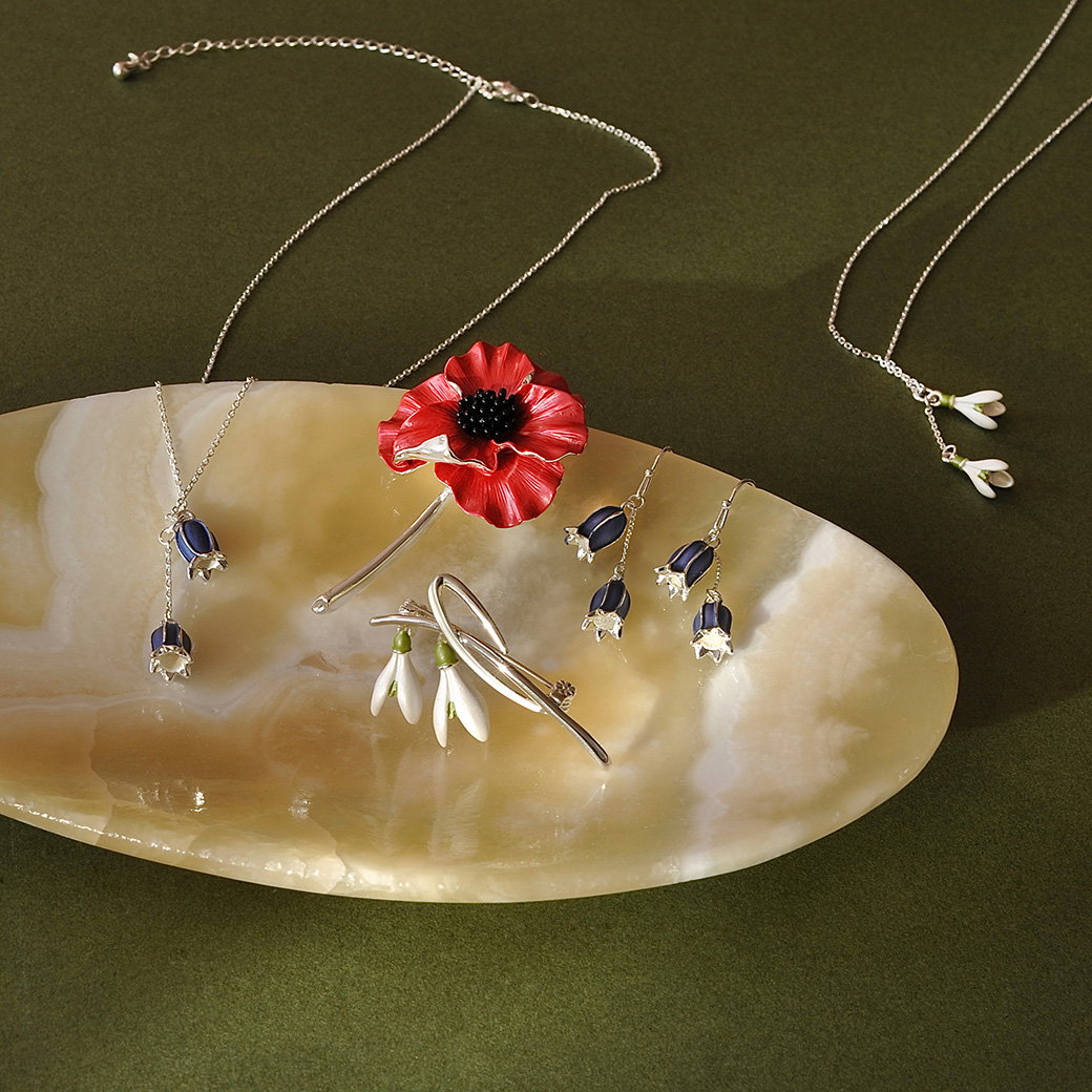 A selection of Mary Delany-inspired floral jewellery arranged on a soapstone dish. – Shop the Range.