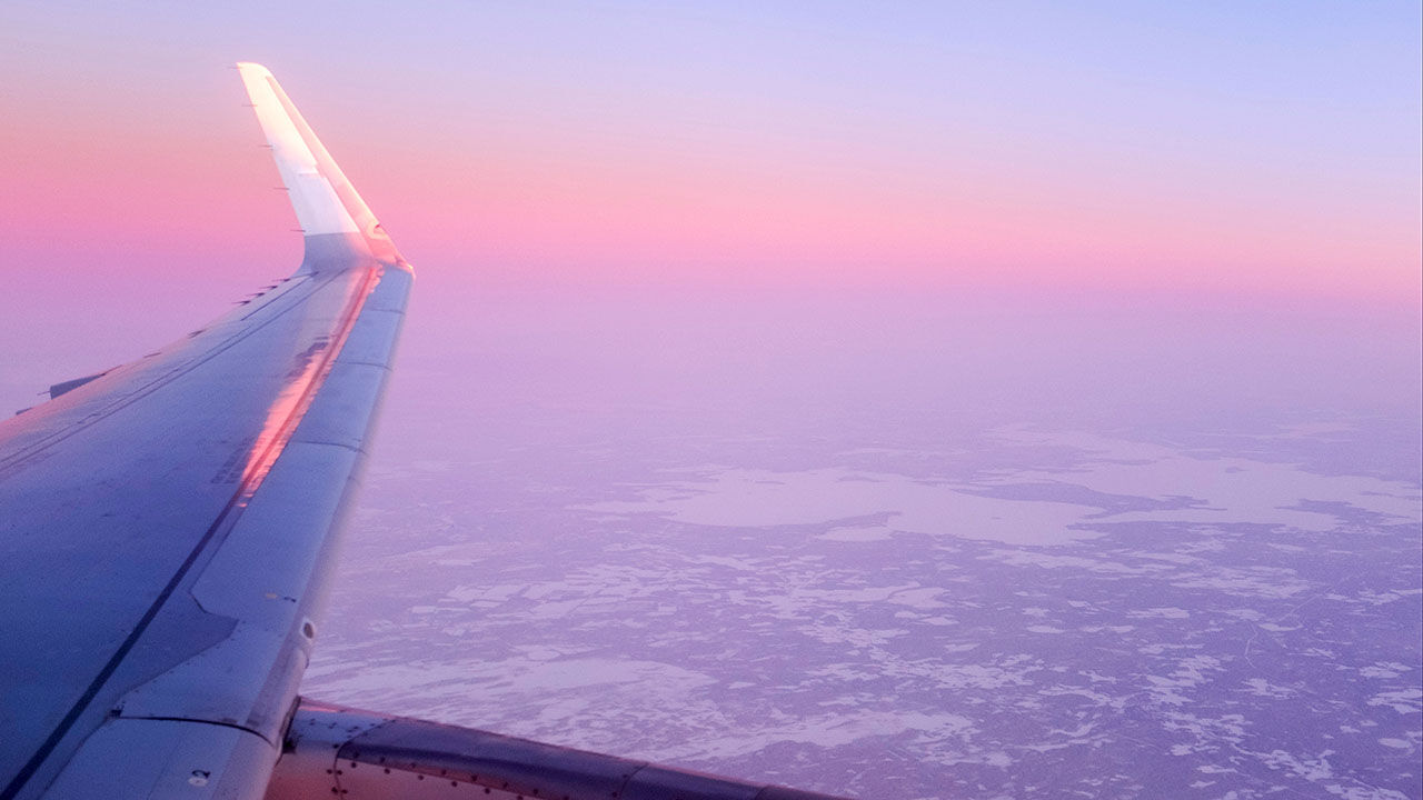 An airplane flying over a snowy landscape in Rovaniemi, Finland at sunset