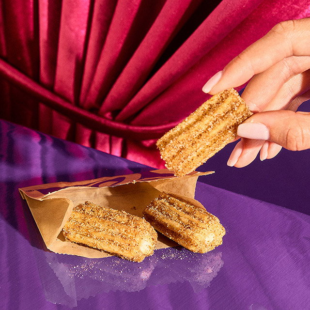 A person picking up a Salted Caramel Churro.