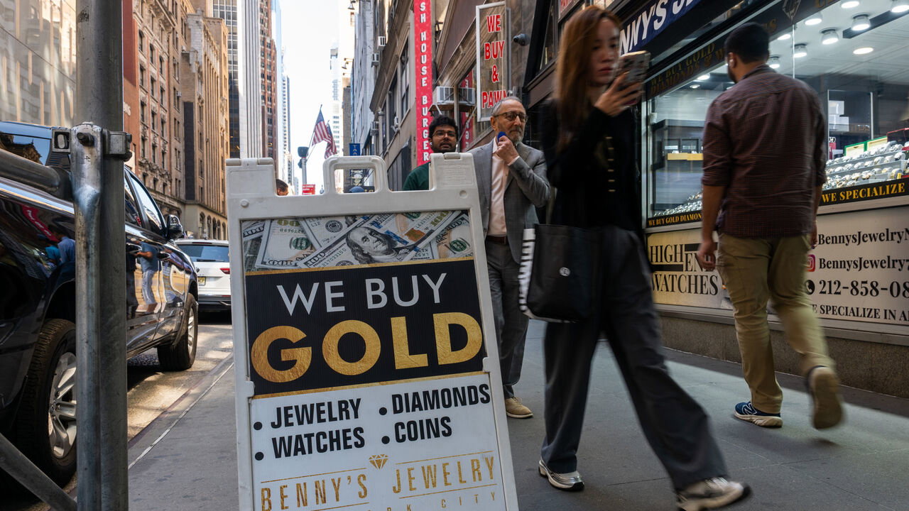 A sign advertises for gold in a window and a sandwich board on the street in Manhattan in New York City, USA.