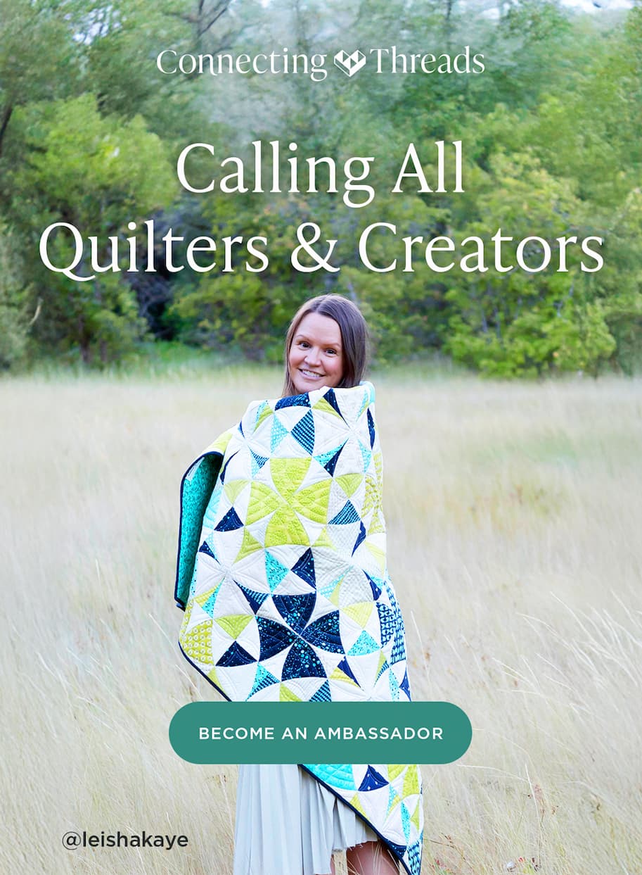Image: A model is wrapped in a green, blue, and white quilt and is standing outside. Text: Connecting Threads. Calling all fabric lovers! Become an ambassador. @leishakaye >>
